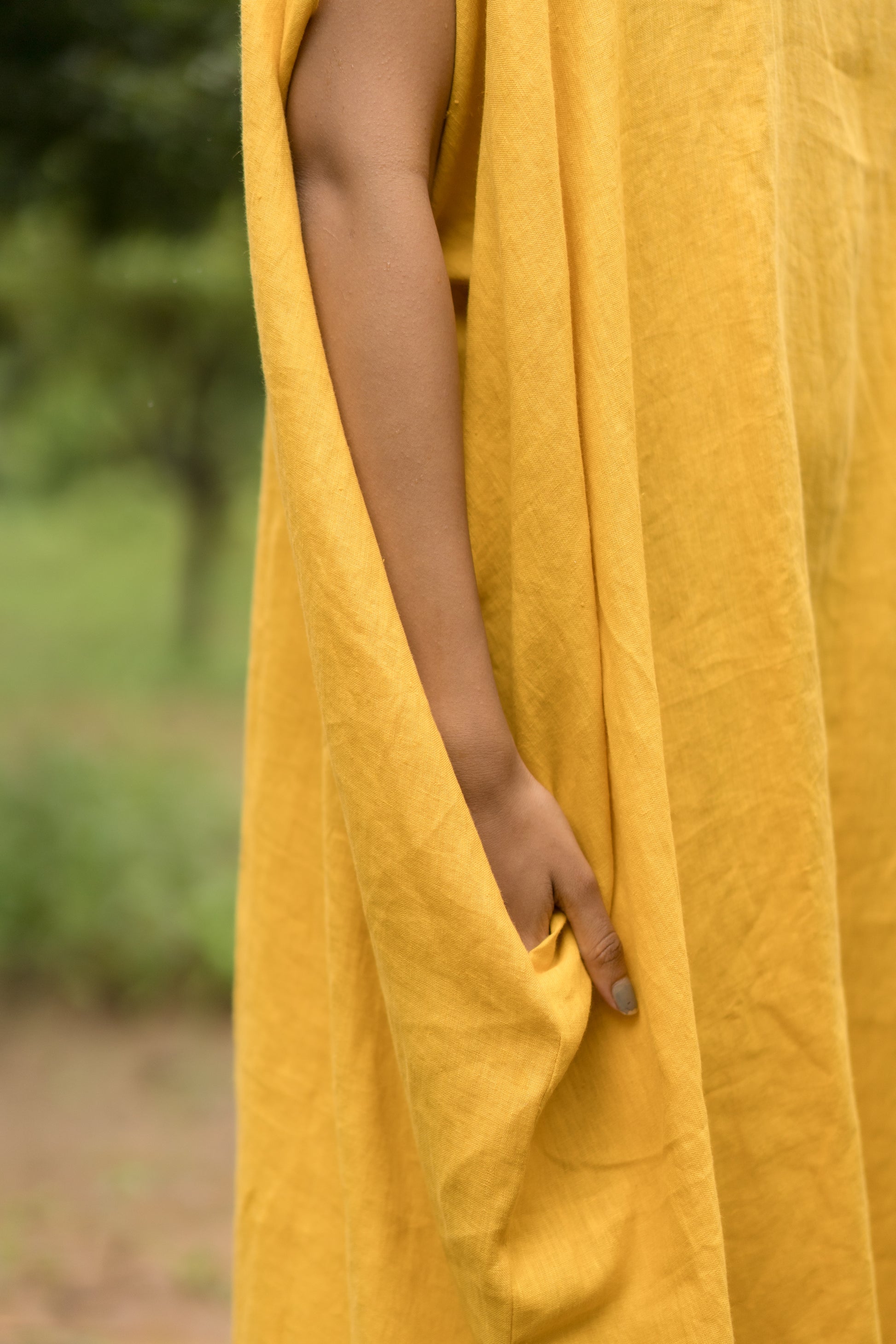 Person wearing a yellow dress with a blurred natural background